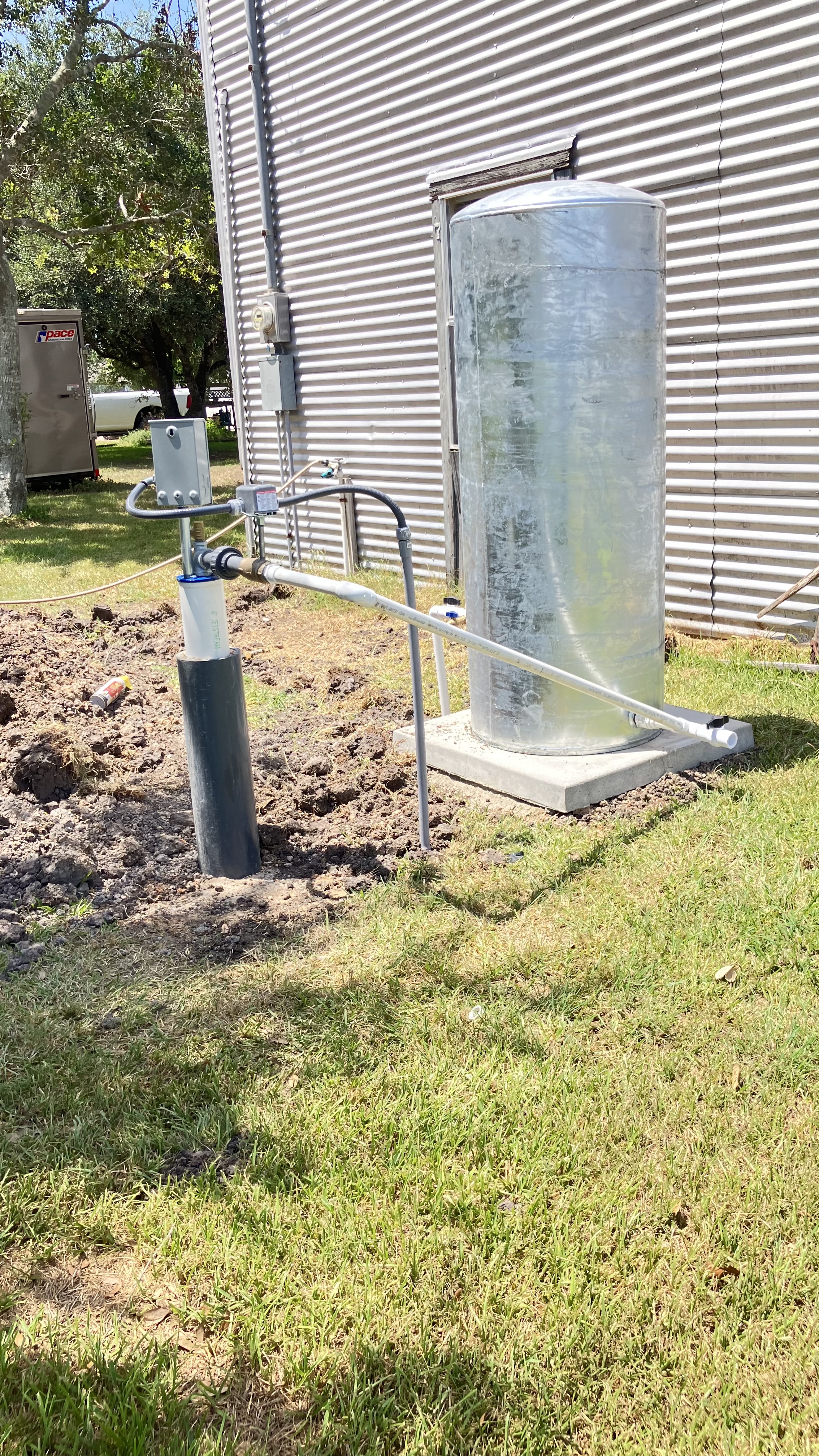 Clean residential well installation with pressure tank and wellhead by Matagorda Water Well